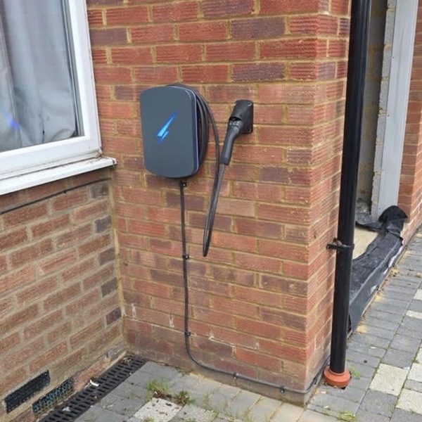EV charger with illuminated bolt installed on a red brick wall