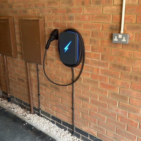 Wall-mounted EV charger with coiled cable on a driveway